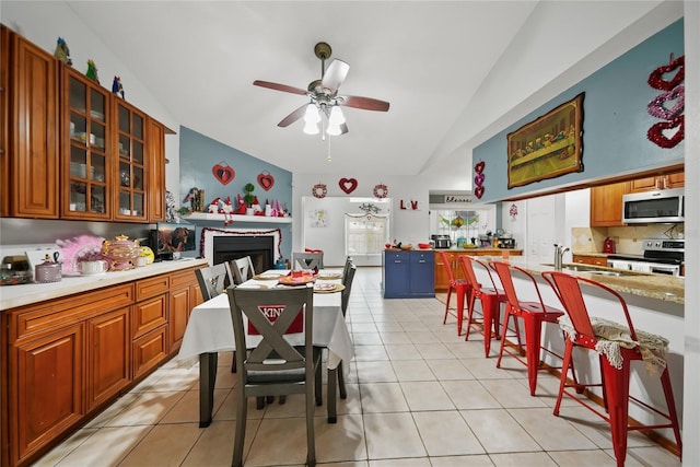 tiled dining room with lofted ceiling, sink, and ceiling fan