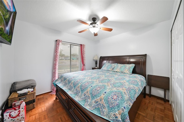 bedroom with dark parquet flooring, ceiling fan, and a closet