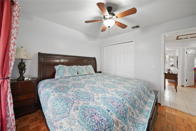 bedroom with ceiling fan, a closet, and dark parquet floors