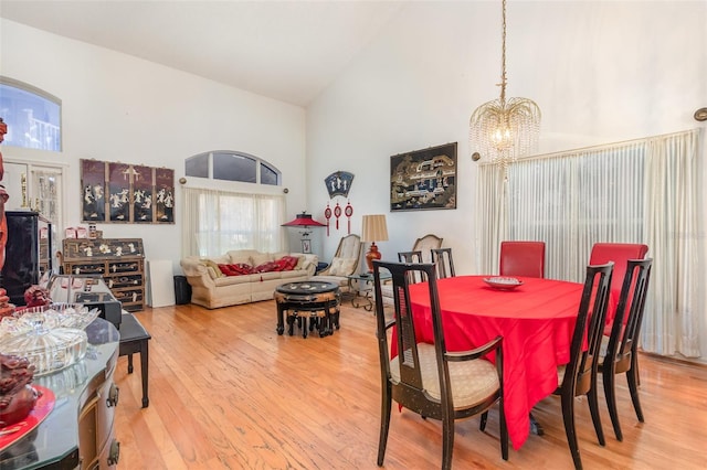 dining area with a chandelier, hardwood / wood-style floors, and high vaulted ceiling