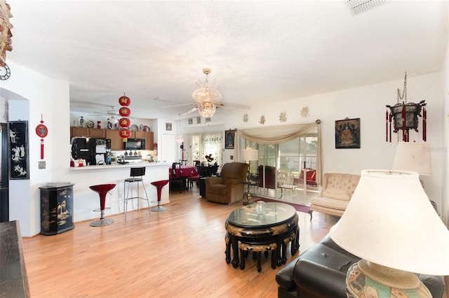 living room with ceiling fan, light hardwood / wood-style flooring, and a textured ceiling