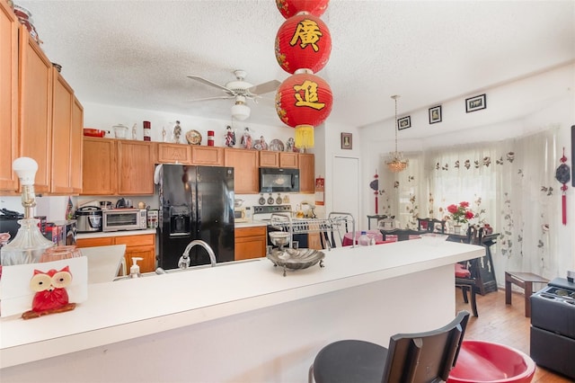 kitchen featuring light hardwood / wood-style flooring, black appliances, kitchen peninsula, and a textured ceiling