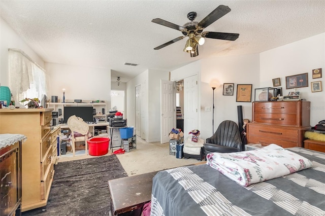 carpeted bedroom with ceiling fan and a textured ceiling