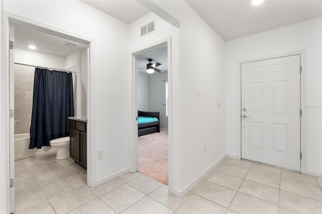 foyer entrance with ceiling fan and light carpet