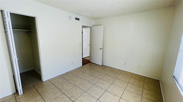 unfurnished bedroom featuring a textured ceiling, a closet, and a walk in closet