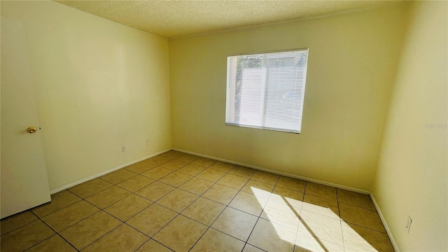 empty room featuring a textured ceiling and light tile patterned floors