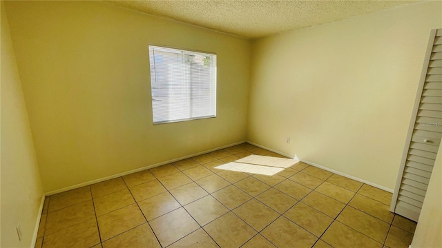 tiled empty room featuring a textured ceiling