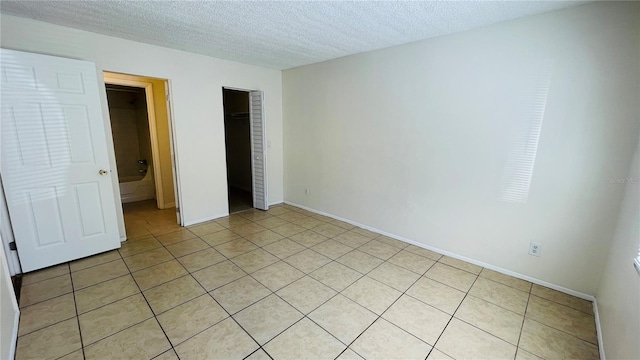 unfurnished bedroom featuring light tile patterned flooring, a textured ceiling, and a closet