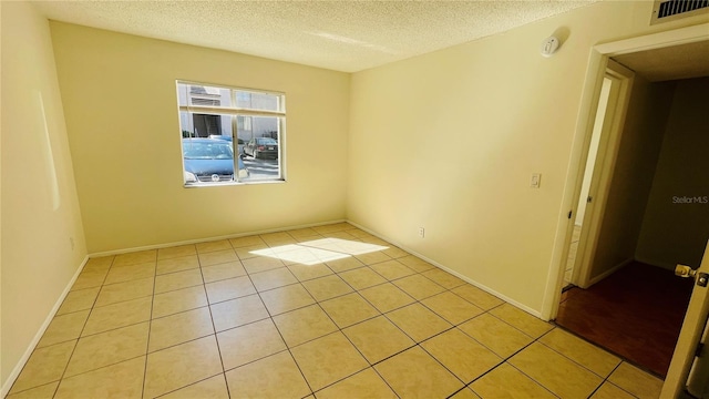 tiled empty room featuring a textured ceiling