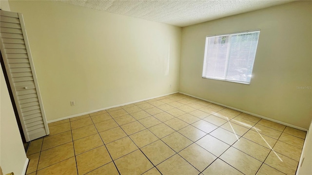 empty room featuring a textured ceiling and light tile patterned flooring