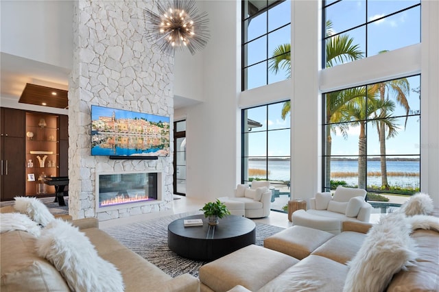 living room featuring an inviting chandelier, plenty of natural light, a stone fireplace, and built in features