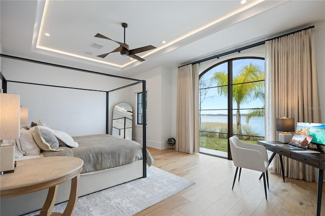 bedroom with a raised ceiling, ceiling fan, access to outside, and light hardwood / wood-style floors