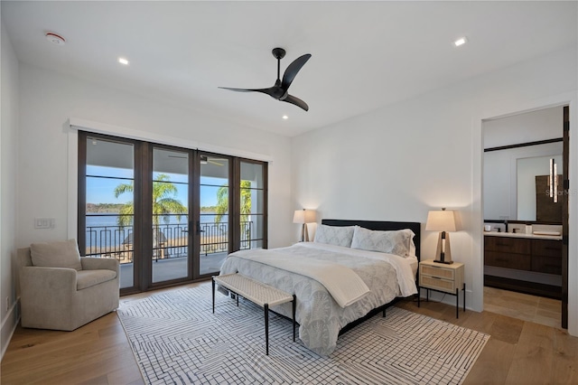 bedroom with light hardwood / wood-style flooring, access to exterior, ensuite bathroom, a water view, and french doors