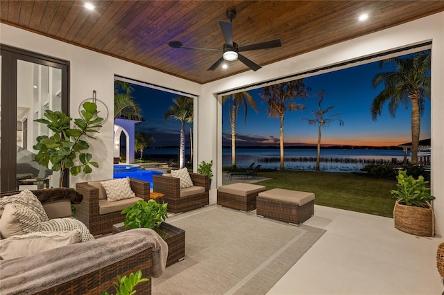 patio terrace at dusk featuring a water view, an outdoor hangout area, and ceiling fan