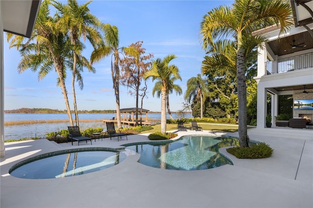 view of swimming pool featuring an in ground hot tub, a water view, ceiling fan, and a patio area