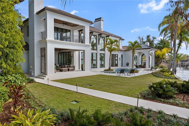 back of property with a patio area, a balcony, a lawn, ceiling fan, and an outdoor hangout area