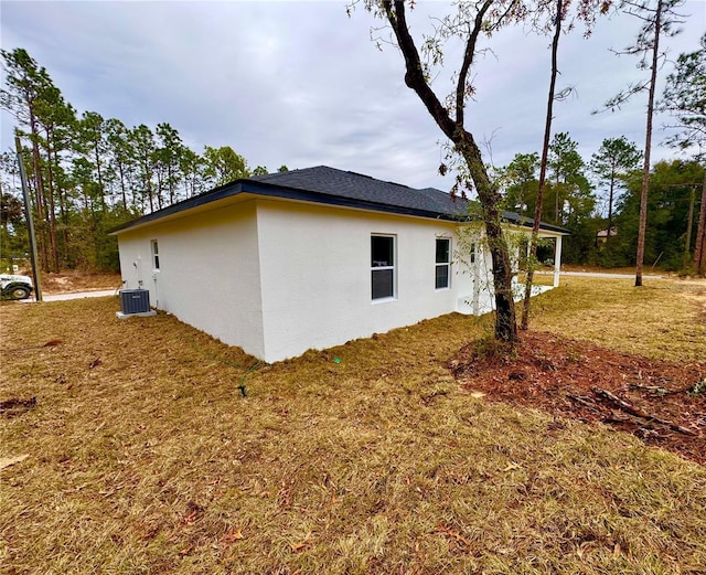 view of side of property with central air condition unit and a yard