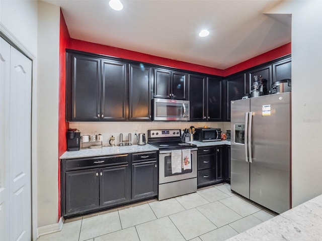 kitchen with light tile patterned floors, stainless steel appliances, and light stone countertops