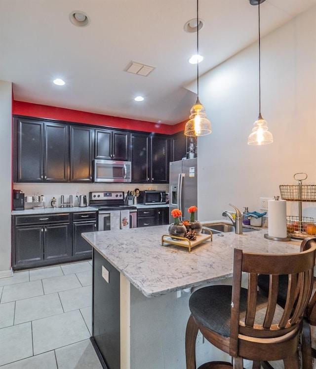 kitchen featuring pendant lighting, sink, a kitchen island with sink, stainless steel appliances, and a kitchen breakfast bar