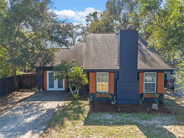 view of front of house featuring driveway, roof with shingles, and fence