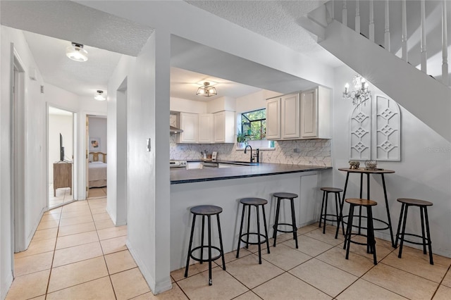 1254 Seminola Blvd, Casselberry, FL 32707 - kitchen featuring a sink, light tile patterned flooring, dark countertops, tasteful backsplash, and a kitchen breakfast bar