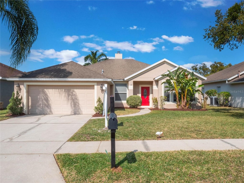 view of front of house with a garage, central AC unit, and a front lawn