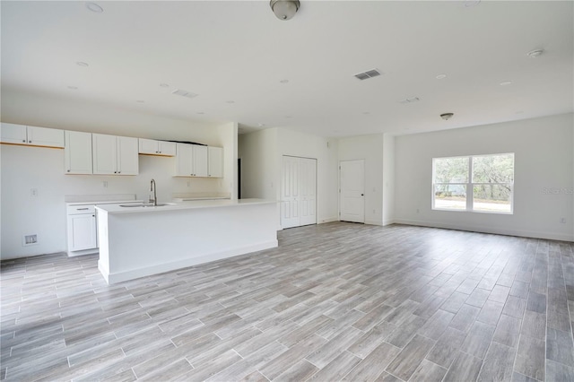 kitchen featuring sink, white cabinetry, and a center island with sink