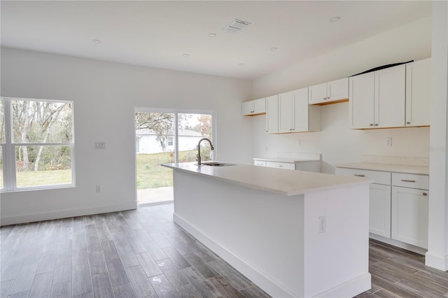 kitchen with sink, light hardwood / wood-style flooring, white cabinetry, and a kitchen island with sink