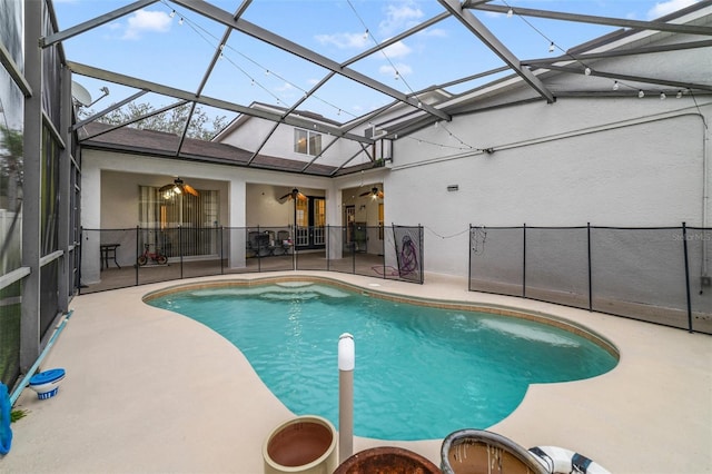 view of swimming pool with ceiling fan, a patio area, and glass enclosure