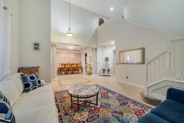 living room featuring a high ceiling, tile patterned floors, and decorative columns