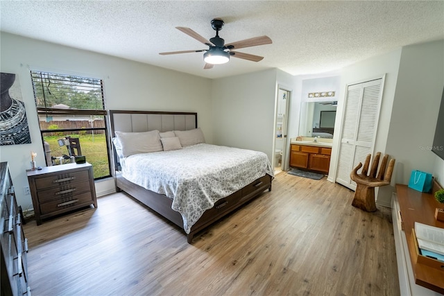 bedroom with ensuite bath, light hardwood / wood-style floors, ceiling fan, a textured ceiling, and a closet