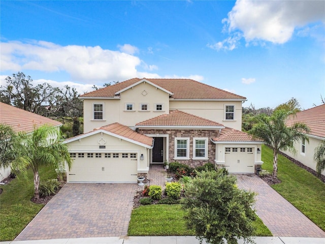 mediterranean / spanish-style house with stone siding, a front lawn, decorative driveway, and a tile roof