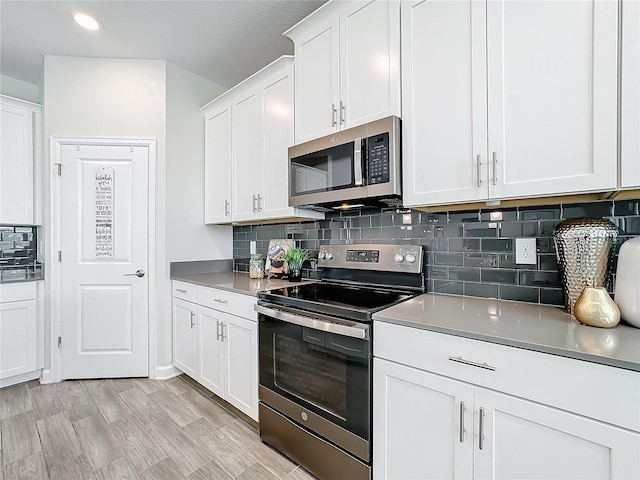 kitchen featuring tasteful backsplash, appliances with stainless steel finishes, white cabinets, and light hardwood / wood-style flooring