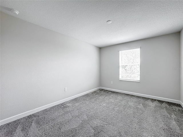 carpeted empty room featuring a textured ceiling