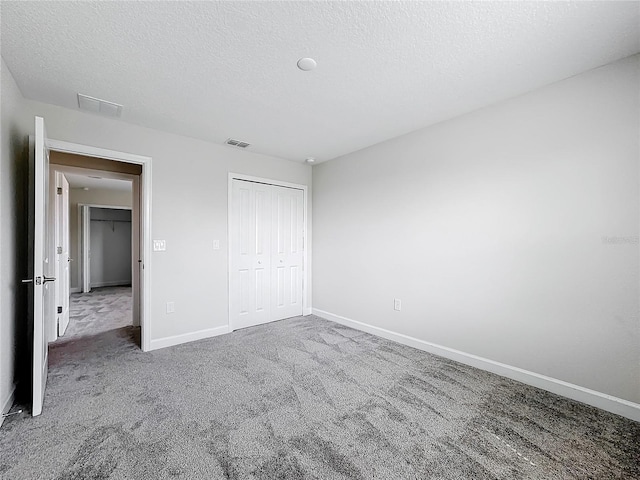 unfurnished bedroom with carpet floors, a textured ceiling, and a closet