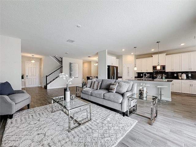 8886 Fallen Oak Dr, Davenport, FL 33896 - living room with stairs, light wood-style flooring, a textured ceiling, and recessed lighting