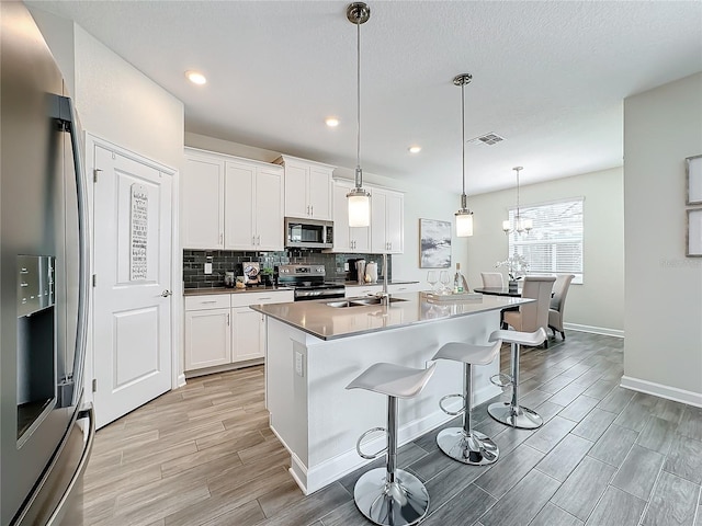 8886 Fallen Oak Dr, Davenport, FL 33896 - kitchen featuring appliances with stainless steel finishes, light wood-style floors, backsplash, a breakfast bar, and white cabinets