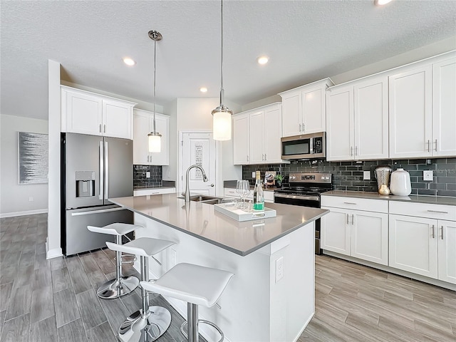 8886 Fallen Oak Dr, Davenport, FL 33896 - kitchen with stainless steel appliances, light wood finished floors, backsplash, white cabinetry, and recessed lighting