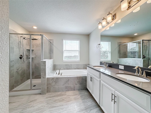 8886 Fallen Oak Dr, Davenport, FL 33896 - bathroom featuring healthy amount of natural light, a garden tub, a stall shower, double vanity, and a textured ceiling