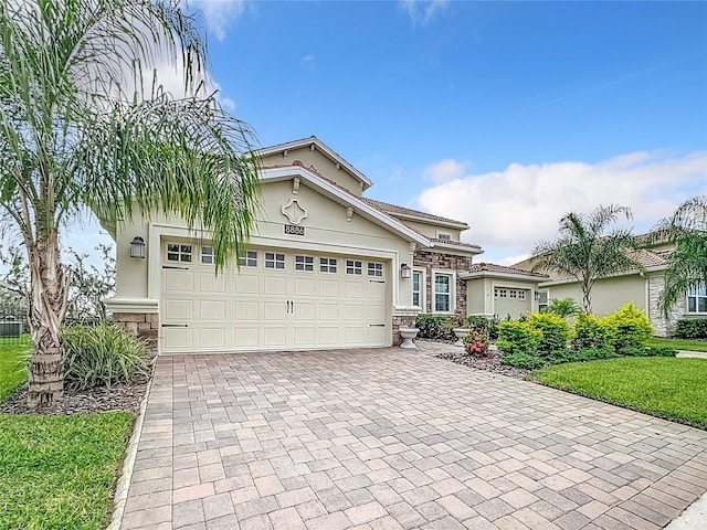 8886 Fallen Oak Dr, Davenport, FL 33896 - view of front of house with stone siding, stucco siding, and a garage
