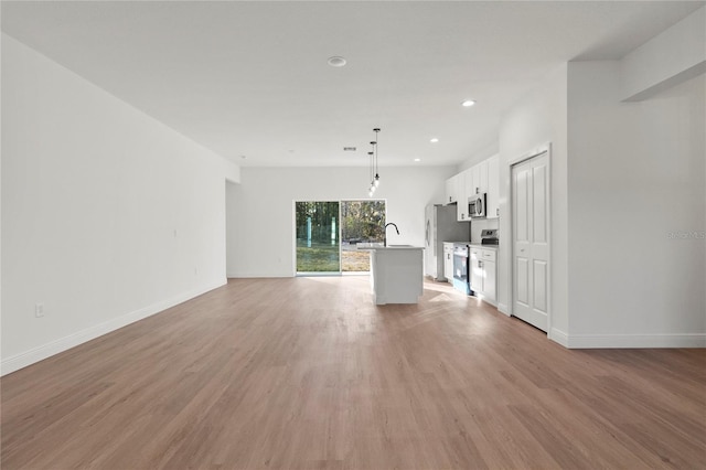 unfurnished living room with light wood finished floors, baseboards, and recessed lighting