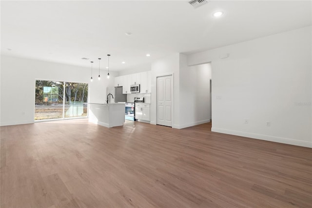 unfurnished living room featuring recessed lighting, visible vents, baseboards, and wood finished floors