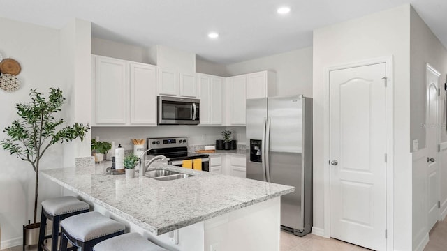 kitchen featuring a breakfast bar, white cabinetry, appliances with stainless steel finishes, and kitchen peninsula