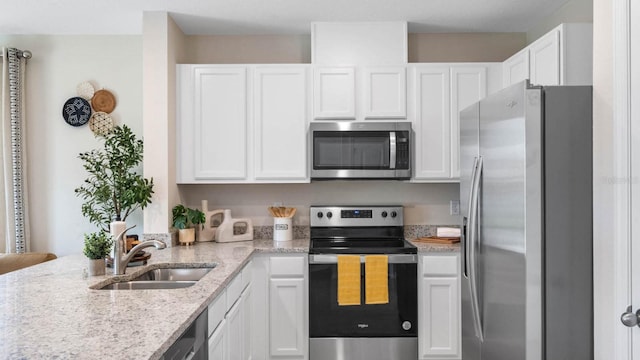 kitchen featuring light stone counters, sink, white cabinetry, and stainless steel appliances