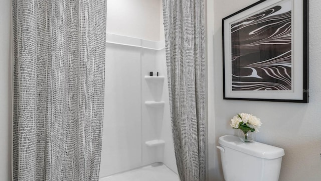 bathroom featuring a shower with curtain and toilet