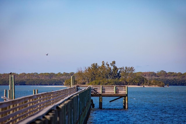 view of dock with a water view and a forest view