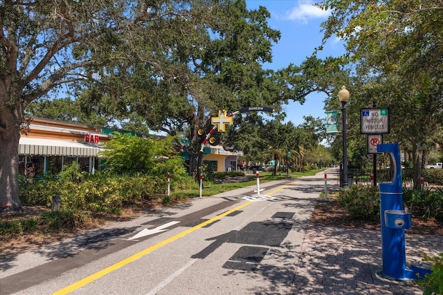 view of road with curbs, street lighting, traffic signs, and sidewalks