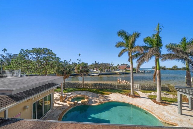 pool with a water view, a patio, and an in ground hot tub