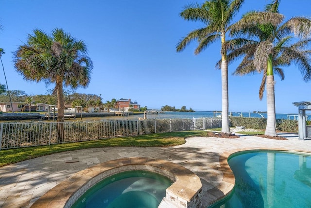 view of pool featuring an in ground hot tub, a patio, a water view, and fence