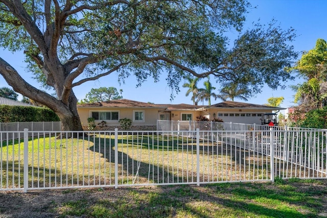 ranch-style house featuring a garage, driveway, stucco siding, fence private yard, and a front yard